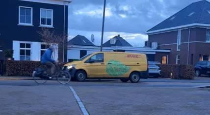 A cyclist passes a DHL delivery vehicle in Doetinchem, Netherlands. March 15, 2026.