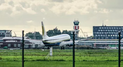 A plane touching down at Rotterdam The Hague airport with the control tower and other airport buildings in the background, 