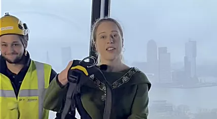 Standing on the observation deck of the Euromast, Mayor Carola Schouten is handed an abseiling harness by a worker wearing a vest from Sky-Access, the company handling renovations of the 185-meter Rotterdam tower. 17 Mar. 2026