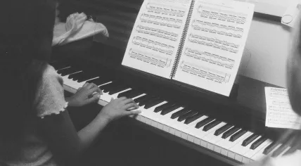 A young girl playing piano during a lesson as her instructor looks on. Jan. 2026