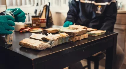 Large amounts of cash seized during a search linked to a Schiphol Airport drug smuggling investigation. 2026