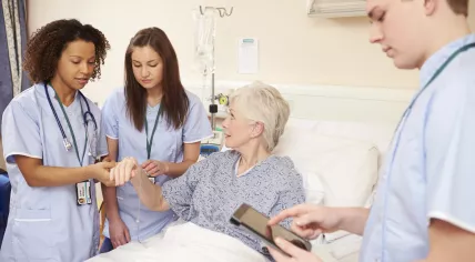 A nurse and two trainees checking on an elderly patient.