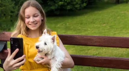 A girl takes a selfie with her puppy.