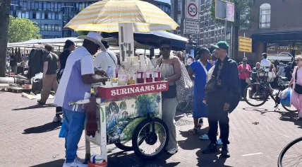 People gather at a Surinamese shaved ice stand on the Dappermarkt in Amsterdam. 25 May 2026