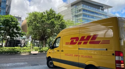 A yellow DHL van parked on a sidewalk at the Hong Kong Science Park. 2021