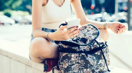 Middle section of a young woman scrolling on a smartphone