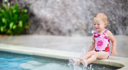 A baby plays with pool water.