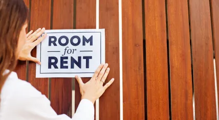 Owner hanging up sign saying room for rent