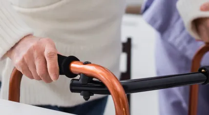A caregiver assisting an elderly individual with a mobility walker.