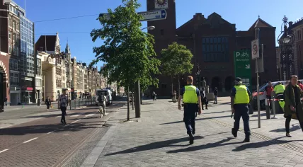 A Handhaving security patrol on Damrak approaching Beursplein in Amsterdam Centrum