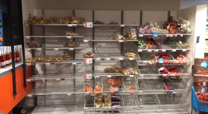 Rows of empty shelves which normally would hold potatoes and onions