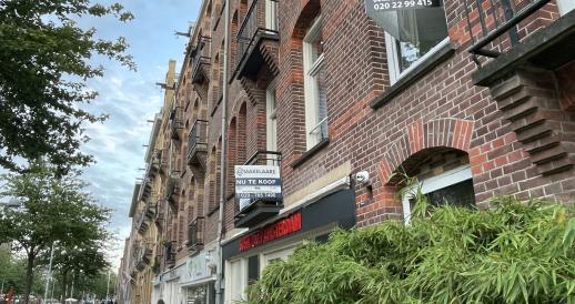A woman walks by two homes for sale on the Javastraat in Amsterdam-Oost in July 2023.