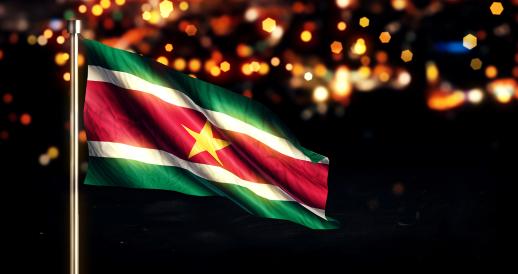 The flag of Suriname against a backdrop of city lights. Artist's rendering.