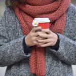 A woman bundled up with a warm drink