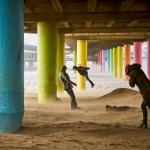 People walk against the wind under a pier on the beach of Scheveningen during Storm Eunice.