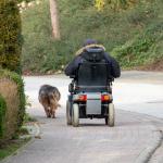 A man drives an electric wheelchair down the road.