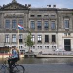 A woman cycles across the water from the Allard Pierson Museum in Amsterdam. 17 May 2018