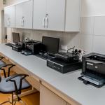 Electronics, computers, and printers on a long desk in an office
