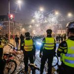 Police officers in the Netherlands look out at a group of people on the street as fireworks explode over their head just after midnight on New Year's Day.