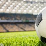 A football on a grass field in a stadium