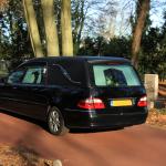 A black hearse at a cemetery in the autumn