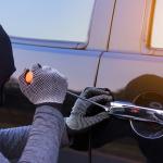 A burglar trying to break into a car with a screwdriver