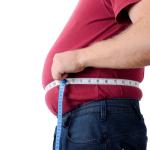 Side view of an overweight man measuring his stomach