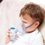 Sick boy sitting with a nebulizer at home