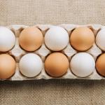 White and brown eggs laying in egg carton on sackcloth