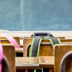 Backpacks hanging on the backs of chairs in a primary school classroom