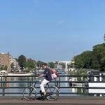 Looking west as a bicyclist crosses Oostenburgergracht in Amsterdam on a sunny morning. 15 July 2024