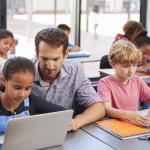 Teacher helping a child on a laptop
