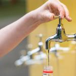 Woman filling a plastic bottle with water from a tap