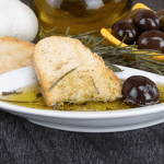 Bread dipped in olive oil with herbs and olives