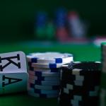 A player sitting at a casino playing cards in front of a stack of chips. 2021