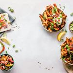 A collection of ingredients, including a salad, guacamole, spring onions, tomatoes, red onions, sour cream, and sweet potato fries. 12 November 2018