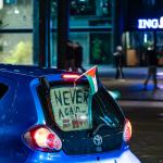 A blue car with Palestinian flags and a sign reading "never again" driving over the Coolsingel in Rotterdam as local Palestinians celebrate a ceasefire agreement between Israel and Hamas, 15 January 2025