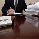 A bankruptcy administrator sitting at a desk with a big pile of papers
