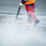 Worker uses a pressure washer to clean the streets.