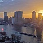 The sun rises over the Erasmus Bridge, De Rotterdam, and the Cruise Terminal along the Nieuwe Maas River and the Kop van Zuid in Rotterdam. 7 Mar 2025