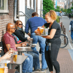 A waitress brings drinks to a customer on a terrace in Amsterdam