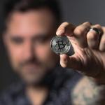 A man holding a coin to represent Bitcoin tokens