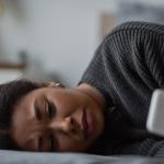 A woman looks at her phone, visibly distressed.
