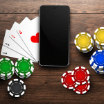Online casino, mobile casino, top view of a mobile phone, chips cards on a wooden background