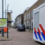 A woman was found murdered in her home on Molenstraat in Hellevoetsluis on 16 April 2025. The photo shows a mobile police unit and crime scene tape cordoning off the scene.
