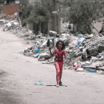 A child walks throuhg rubble in Gaza on her way to get food, 25 August 2024