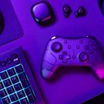 Blue lit keyboard amidst various modern gaming devices