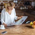 A woman is reading a newspaper.