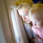 A baby and her mother looking through an airplane window