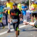 Volunteer giving water to runners on the road during a marathon.